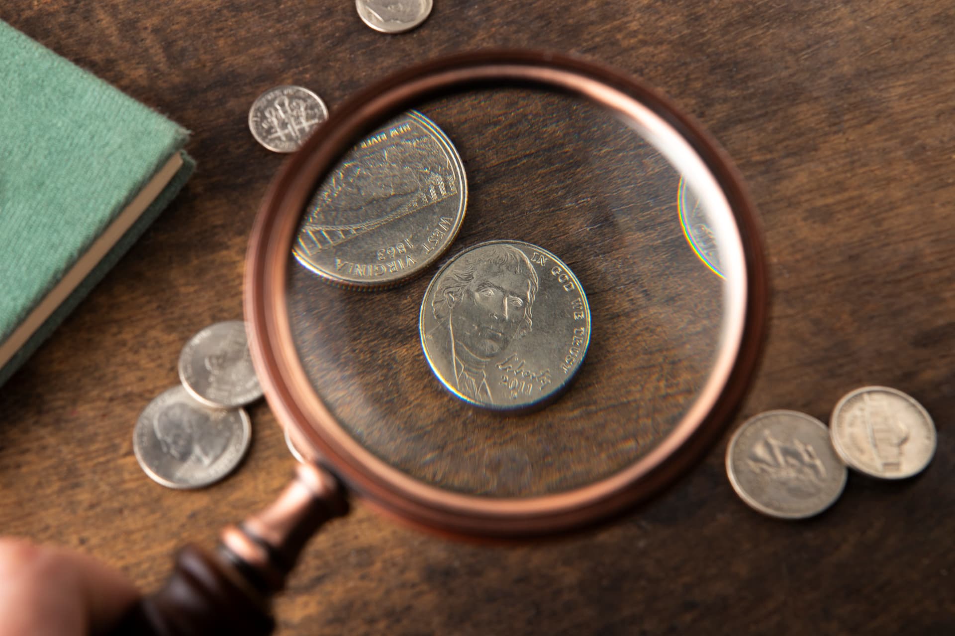 Lupa ampliando uma moeda sobre uma mesa com outras moedas